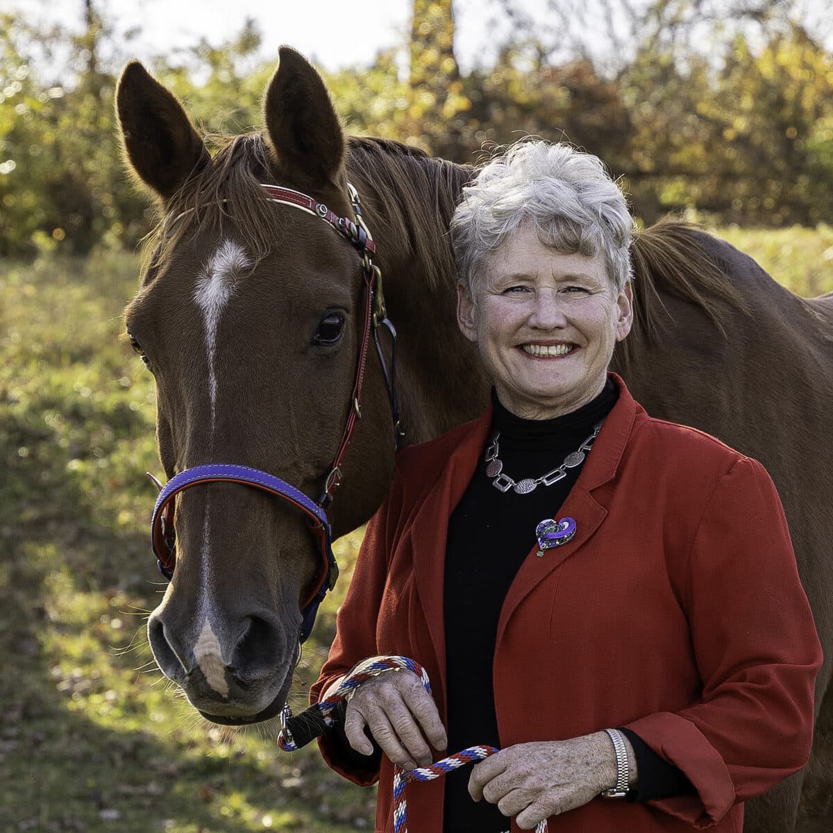 Holly Corcoran smiling beside her horse, Poete.